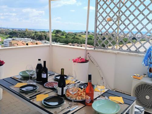 una mesa con botellas de vino y copas en el balcón en Attico di Design vista mare, en Santa Marinella