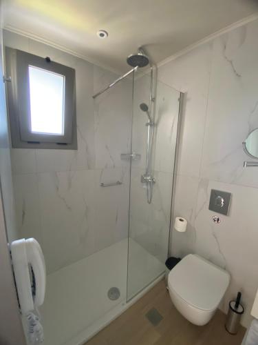 a white bathroom with a shower and a toilet at Barbie Hotel Apartments in Ialyssos