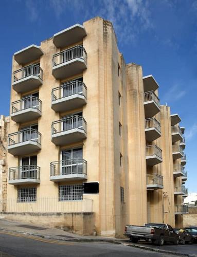 um edifício alto com varandas e um camião estacionado em frente em Standard 1 bedroom Balluta Bay (5) em Sliema