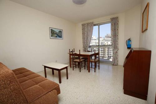 uma sala de estar com um sofá, uma mesa e cadeiras em Standard 1 bedroom Balluta Bay (5) em Sliema