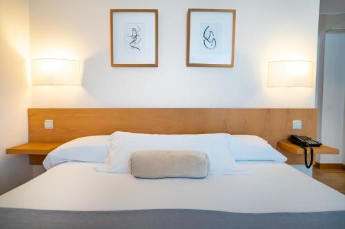 a bedroom with a white bed with two pictures on the wall at Gran Hotel Victoria in Santander