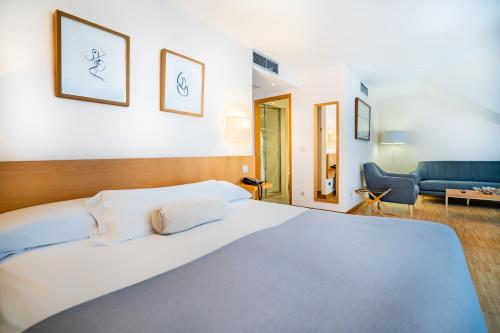 a bedroom with a large white bed and a couch at Gran Hotel Victoria in Santander