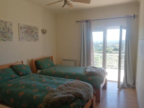 a bedroom with two beds and a sliding glass door at Chambres D'Hôte in Bensafrim