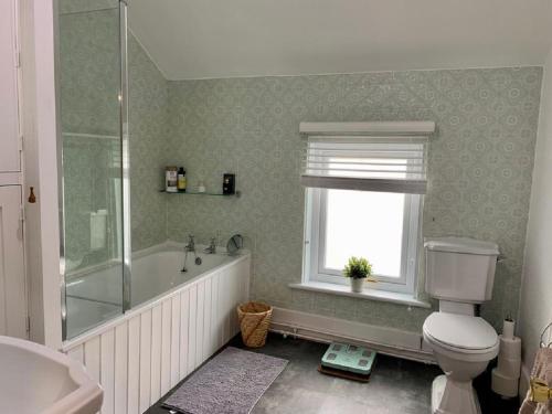 a bathroom with a tub and a toilet and a window at North View House Next to Hadrian's Wall in Gilsland