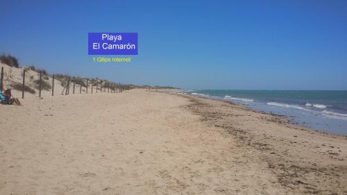 a beach with a blue sign that reads play e canon at La Pavona 11 - 1ª línea de Playa Chipiona in Chipiona
