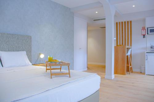 een slaapkamer met een wit bed en een tafel bij Casal da Penha Apartments in Funchal