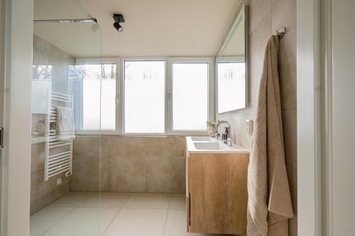 a bathroom with a sink and a shower with windows at Buiten aan zee by Droomvilla in Sint Maarten