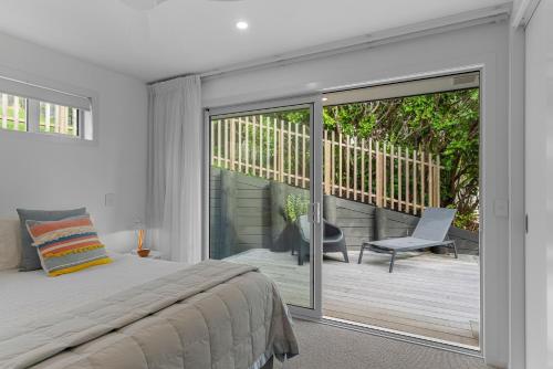um quarto com uma cama e uma porta de vidro deslizante em Coastal Cool - Luxury Langs Beach Accommodation em Langs Beach
