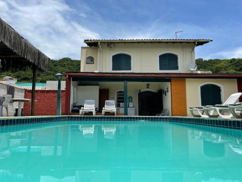 a villa with a swimming pool in front of a house at Sunset Hostel Guarujá in Guarujá