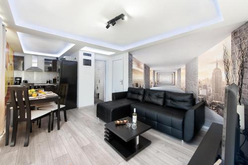 a living room with a black couch and a kitchen at GR House Eleftheria in Afantou