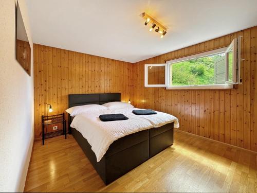 Chez Tonton في سيون: غرفة نوم بسرير ونافذة وجدران خشبية