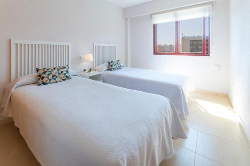 two beds in a white room with a window at AG SALINAS in Playa de Gandia