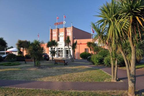 un bâtiment avec un panneau au-dessus de celui-ci et des palmiers dans l'établissement Superbe maison face mer à Pirou, à Pirou