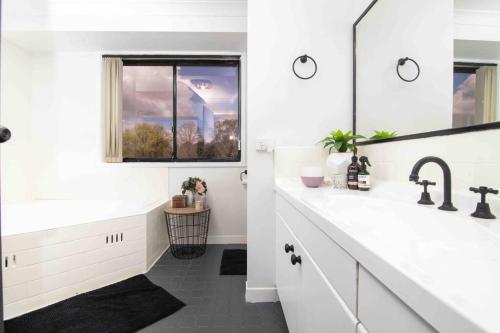 a white bathroom with a sink and a mirror at Blue Willow Bathurst Country Getaway in Bathurst