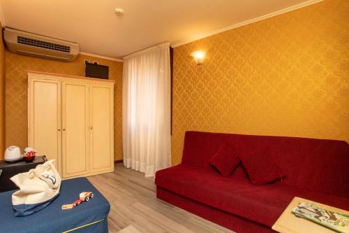 ein Wohnzimmer mit einem roten Sofa und einem Schrank in der Unterkunft Hotel Tintoretto in Venedig