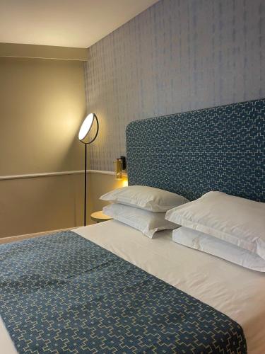 a bedroom with a large bed with a blue headboard at Hotel Restaurant Christophe Colomb in Calvi