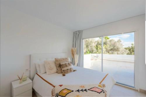 Dormitorio blanco con cama y ventana grande en Villa Daniel, en Sant Jordi