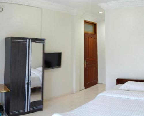 um quarto com duas camas e uma televisão na parede em Flamboyan House em Padang