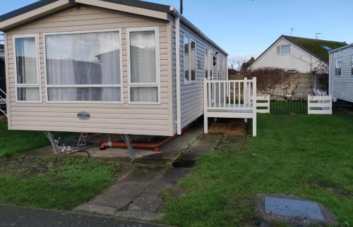 a tiny house with a porch and a bench at The Ruby Lido Beach Prestatyn in Prestatyn