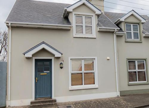 a white house with a blue door and windows at Kilkee Townhouse by Trident Holiday Homes in Kilkee