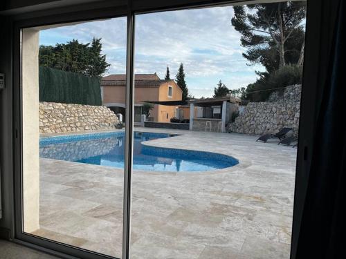 a view of a swimming pool through a window at Jolie maison avec vue sur piscine in Bouc-Bel-Air