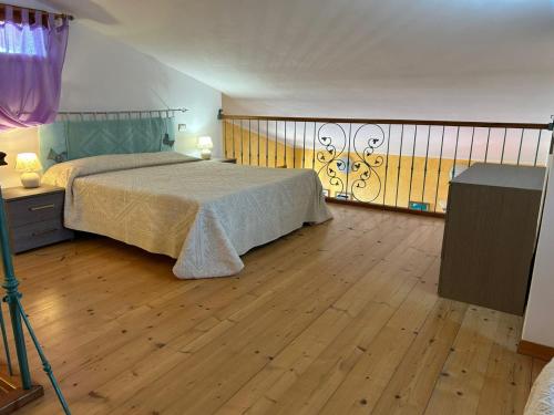 Schlafzimmer mit einem Bett und Holzboden in der Unterkunft Casa sulla collina - Sant'Antioco in SantʼAntìoco