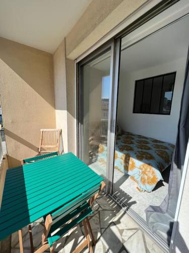 een balkon met een groene bank en een glazen schuifdeur bij Appartement - Nice promenade in Nice