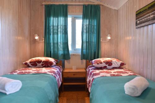 a room with two beds and a window with green curtains at Laxás Cottage in Blönduós