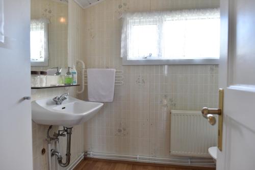 ein weißes Bad mit einem Waschbecken und einem Fenster in der Unterkunft Laxás Cottage in Blönduós