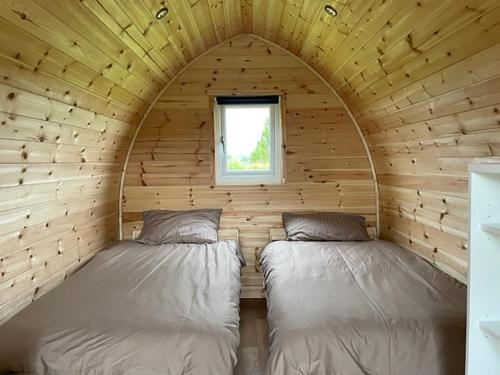2 camas en una cabaña de madera con ventana en F&H Camping, en Danby