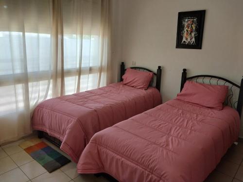 Appartement Hay Riad في الرباط: سريرين في غرفة ذات أغطية وردية