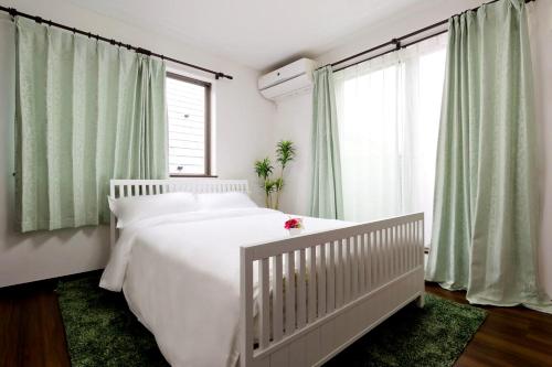 1 cama blanca en un dormitorio con cortinas verdes en 新宿顶级奢华三层独栋别墅/车站5分钟/儿童房/8人, en Tokio
