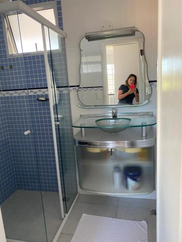uma mulher tirando uma foto de um lavatório na casa de banho em Apartamento enseada Guarujá no Guarujá