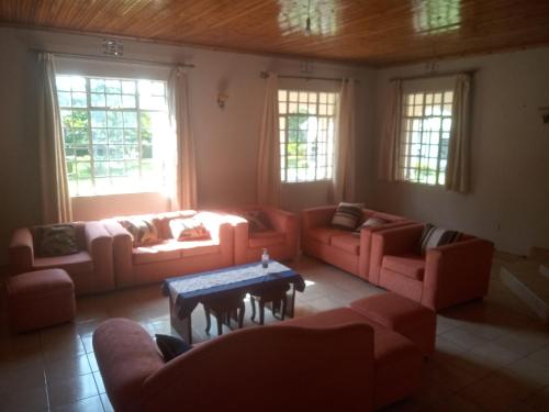 a living room with couches and a table and windows at Key's Place in Ambira