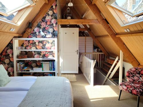 um quarto no sótão com uma cama e uma estante de livros em De Buurvrouw Nr.18 em Doesburg
