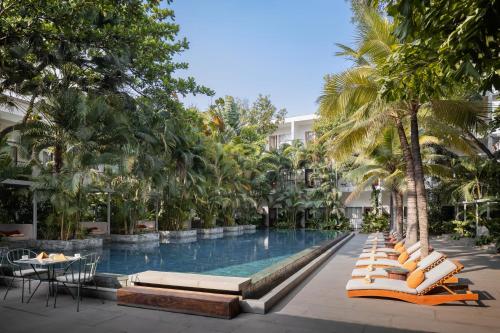 - une piscine dans un complexe avec des chaises longues et des palmiers dans l'établissement Plantation Urban Resort & Spa, à Phnom Penh