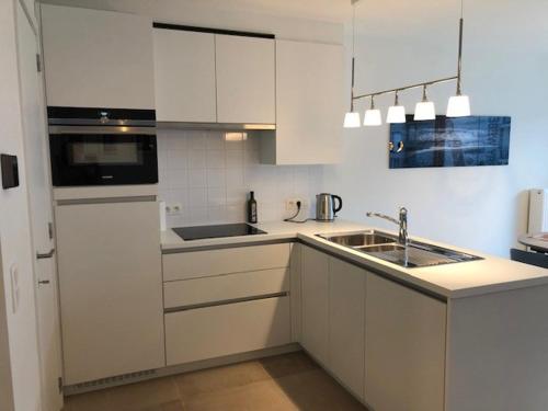 a white kitchen with a sink and a microwave at Monico 0202 ref 49 in Koksijde