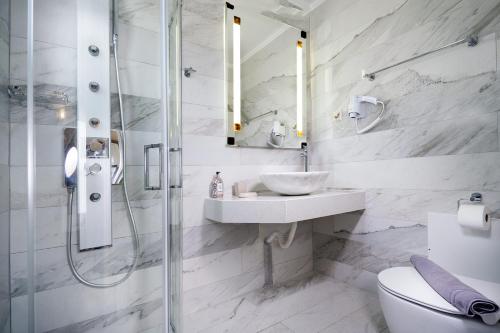 Un baño blanco con ducha y lavabo. en Beach Villas, en La Canea