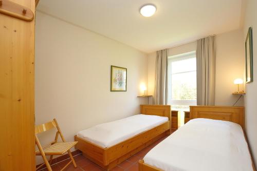 a room with two beds and a chair and a window at Dünenblick Wohnung 20 in Boltenhagen