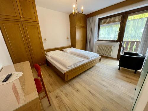 a bedroom with a bed and a desk and a table at Garni Transit B&B - Your Stopover in Vipiteno