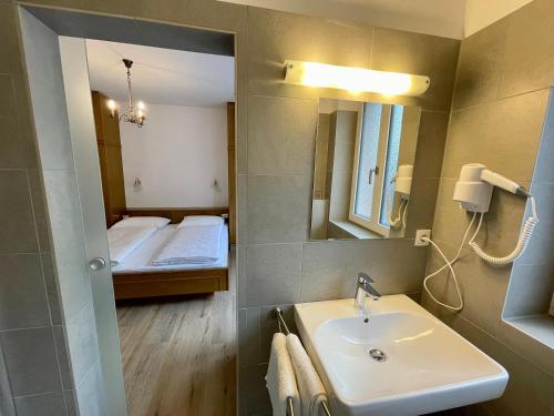 a bathroom with a sink and a bed and a mirror at Garni Transit B&B - Your Stopover in Vipiteno