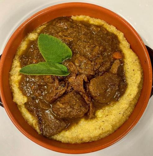 a bowl of meat stew with a green leaf on top at CASCINA DOMINA in Gassino Torinese