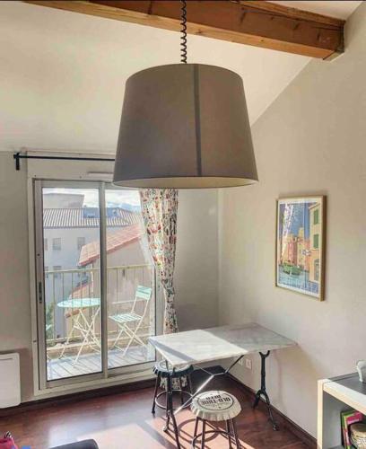 um quarto com uma mesa, um candeeiro grande e uma varanda em Le Matabiau - Confortable T1bis proche gare em Toulouse