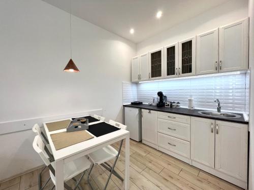 a kitchen with white cabinets and a sink and a table at Centrum in Novi Sad