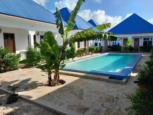 a villa with a swimming pool in front of a house at Serenity 2 - Jambiani in Jambiani