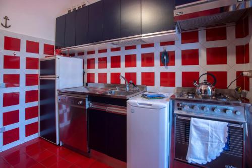 a red and white kitchen with a stove and a sink at 080 - La Villa storica Il Vigneto 45b, Terrazza sul Mare - Parcheggio privato GRATIS in Moneglia