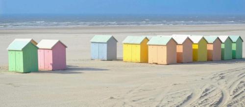 une rangée de cabanes de plage colorées sur une plage dans l'établissement le bien être, à Berck-sur-Mer