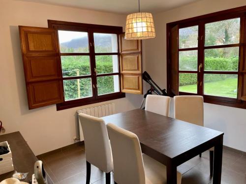 uma sala de jantar com mesa, cadeiras e janelas em Casa Mojapies em Ribadesella