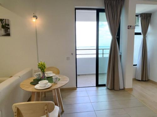 a table and chairs in a living room with a balcony at Mutiara Melaka Beach Resort by Minso in Tangga Batu