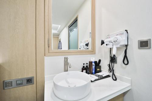 a bathroom with a white sink and a mirror at Ytt Hotel in Busan